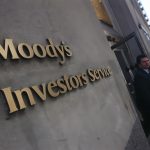 a man in a suit walking past a sign